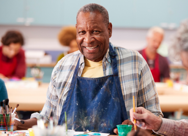 Man smiling at the camera during a painting class.